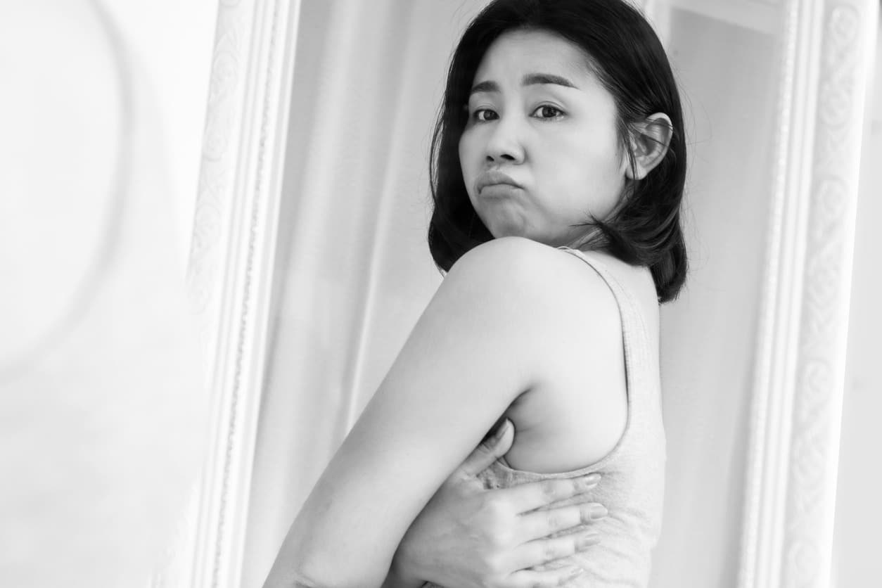 Woman wraps her arms around her back, highlighting her bra fat before Kybella treatment to dissolve it